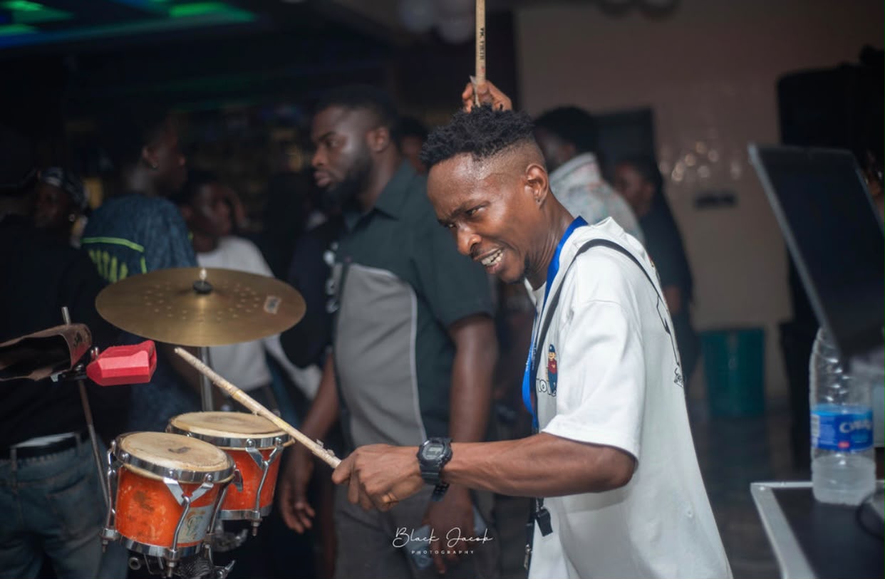 A smiling percussionist playing drums at Steeze After Stress